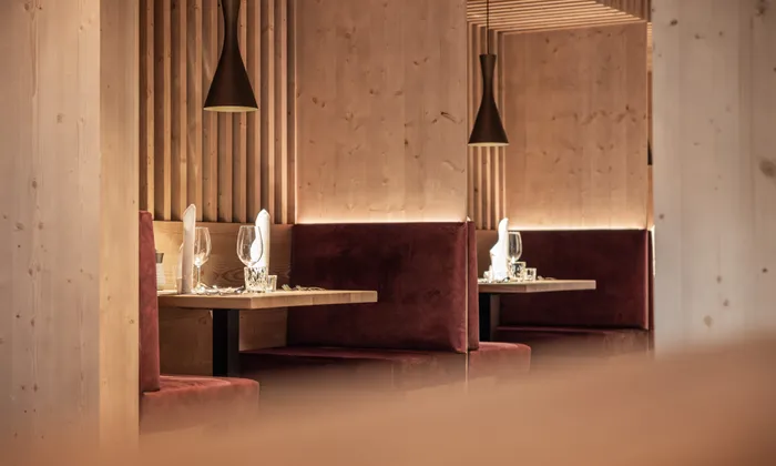 Elegant restaurant booths with wooden walls, red velvet seats and set tables